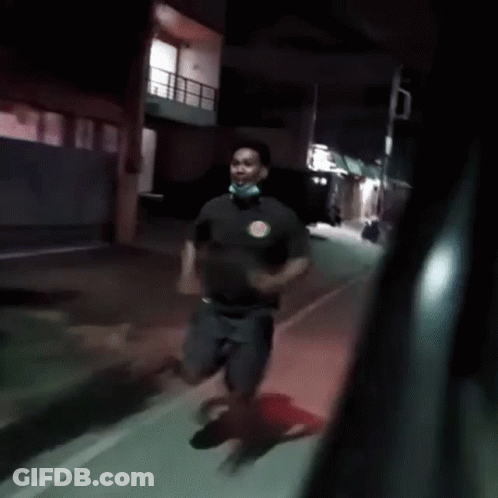 Man In Mask Running Down Street At Night GIF