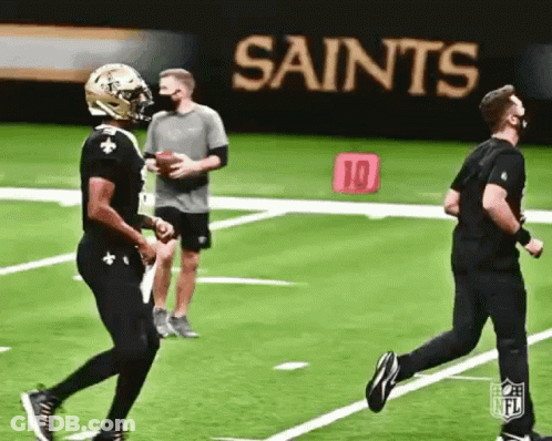 Man In Mask Running On Football Field While Another Throws Ball GIF