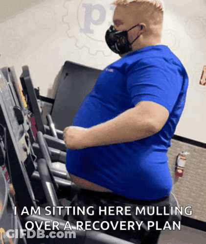 Man In Mask Sitting On Treadmill Saying I Am Sitting Here Mulling Over A Recovery GIF