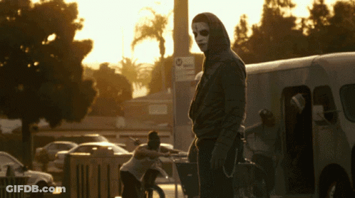 Man In Mask Standing In Front Of No Parking Sign GIF