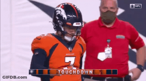 Man In Mask Standing Next To Football Player In Orange Jersey GIF