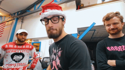 Man In Merry Little Christmas Sweater Next To Two Men GIF