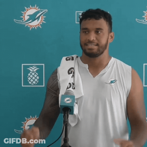 Man In Miami Dolphins Shirt In Front Of Blue Wall GIF