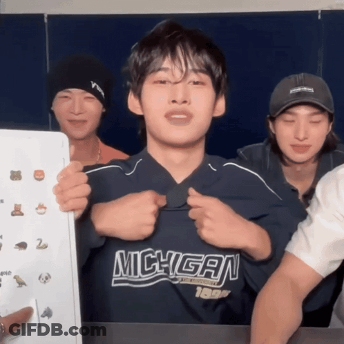 Man In Michigan Shirt Held By Two Men GIF