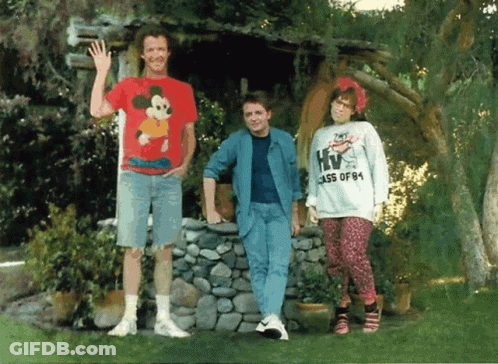 Man In Mickey Mouse Shirt Next To Woman In HIV Class Of '84 Sweatshirt GIF