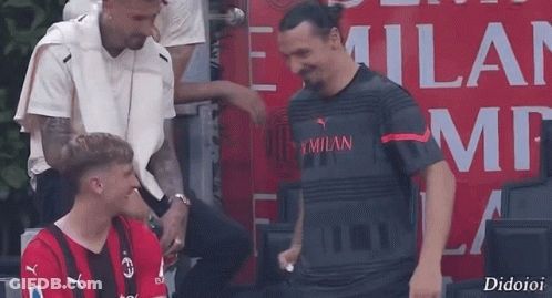 Man In Milan Shirt Talking To Red Shirt Man GIF