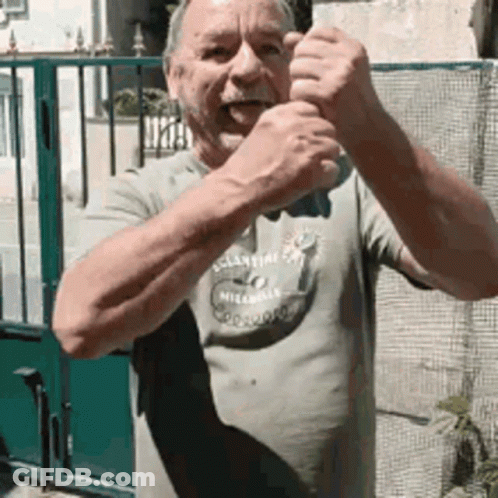 Man In Milano Shirt Standing In Front Of Green Fence GIF