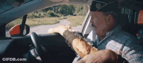 Man In Military Hat Driving Car Holding Bread GIF