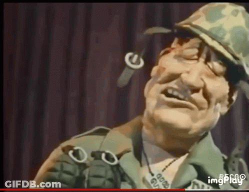 Man In Military Uniform Holding Grenade And Smiling GIF