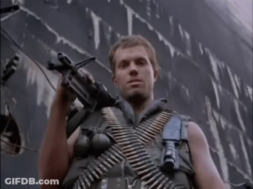 Man In Military Uniform Holding Gun In Front Of Ship GIF