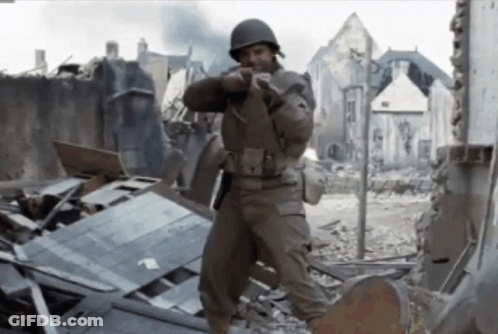 Man In Military Uniform Standing In Destroyed City Holding Gun GIF