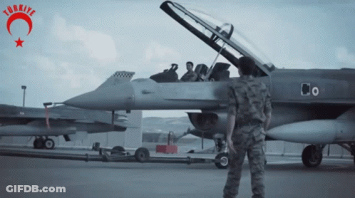 Man In Military Uniform Stands In Front Of Fighter Jet With Word Turkey GIF