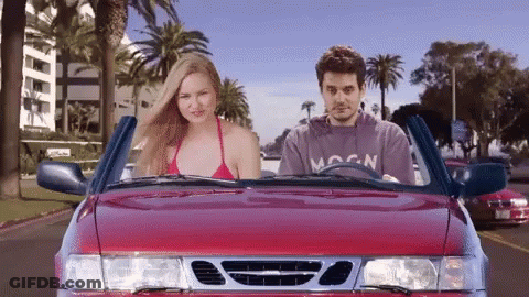 Man In Moon Shirt Driving Red Car With Woman In Bikini GIF