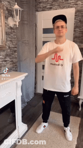 Man In Musical.ly T-Shirt Standing By Fireplace GIF