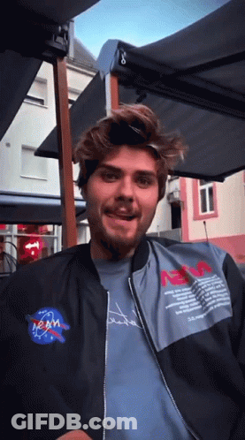 Man In NASA Jacket Sitting Under Umbrella GIF
