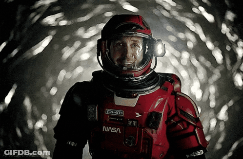 Man In NASA Space Suit Smiling In Dark Room GIF