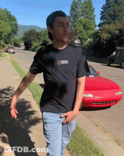 Man In National Geographic T-Shirt Walking Down Sidewalk GIF