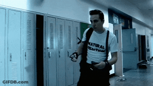 Man In Natural Selection Shirt Walking Down Hallway GIF