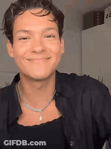 Man In Necklace And Black Shirt Smiling GIF