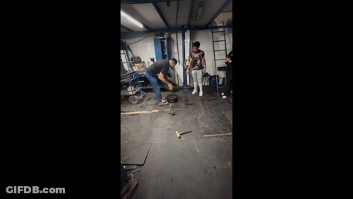 Man In Nike Shirt Kneeling In Garage GIF