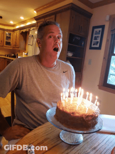 Man In Nike Shirt Sitting At Cake Table GIF