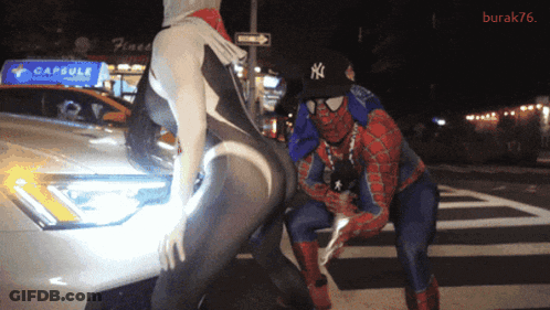 Man In NY Hat Next To Woman In Spiderman Suit GIF