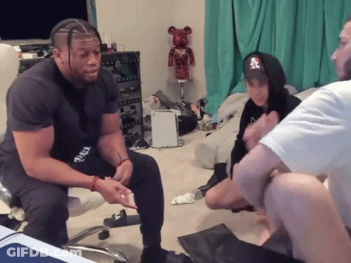 Man In NY Hoodie Sitting With Others GIF