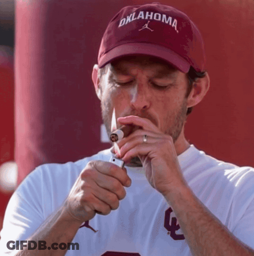 Man In Oklahoma Hat Lighting Cigar GIF