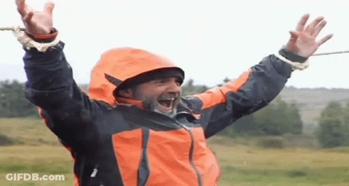 Man In Orange And Black Jacket Laughing Arms Up GIF