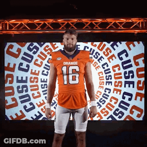 Man In Orange Football Jersey Standing In Front Of Screen GIF