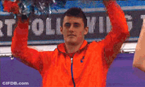 Man In Orange Jacket Holding Cheerleading Pom Pom GIF