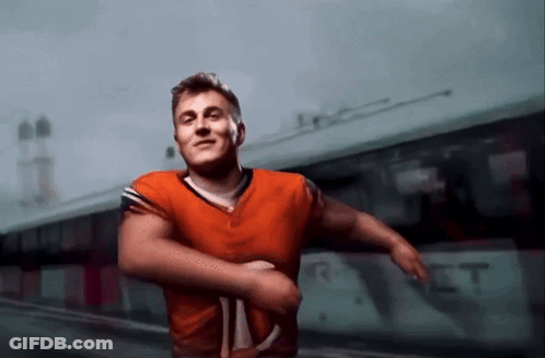 Man In Orange Jersey In Front Of Bus Saying RT GIF