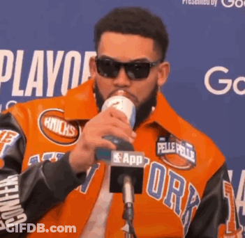 Man In Orange Knicks Jacket Drinking From Can GIF