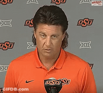 Man In Orange OSU Shirt Standing In Front Of Wall GIF