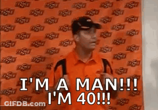 Man In Orange Shirt And Black Hat Saying I'm A Man GIF
