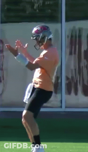 Man In Orange Shirt And Black Shorts Wearing Football Helmet GIF