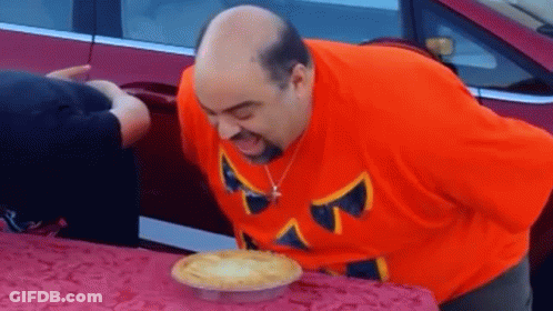 Man In Orange Shirt Blowing Out Pie GIF
