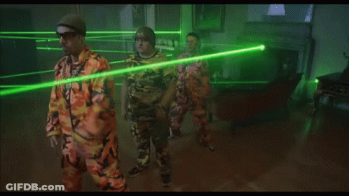 Man In Orange Shirt Facing Green Laser Beams GIF