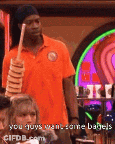 Man In Orange Shirt Holding Bagels Saying You Guys Want Some Bagels GIF