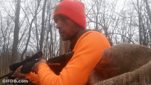 Man In Orange Shirt Holding Gun GIF
