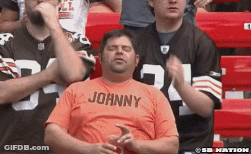 Man In Orange Shirt Johnny Sitting In Stadium GIF