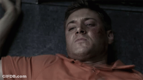 Man In Orange Shirt Laying On Floor Making Funny Face GIF
