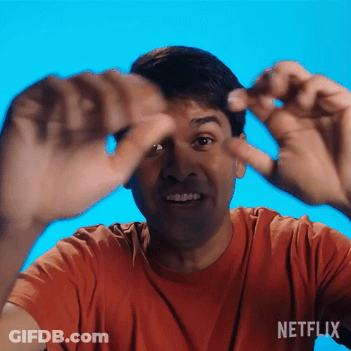 Man In Orange Shirt Making Funny Face In Front Of Netflix Background GIF