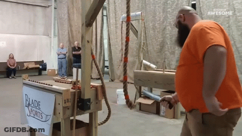 Man In Orange Shirt Standing Before Blade Sports Sign GIF