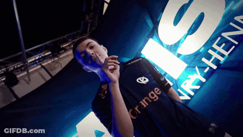 Man In Orange Shirt Standing In Front Of Sign GIF