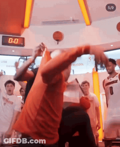 Man In Orange Shirt Throwing Basketball In Front Of Clock Saying 0-0 GIF