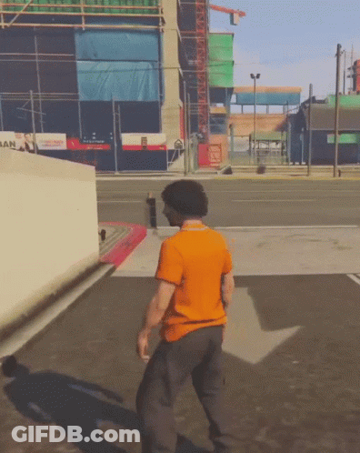 Man In Orange Shirt Walking In Front Of San Building GIF
