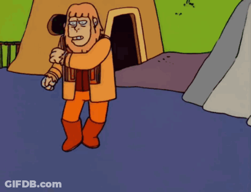 Man In Orange Standing In Front Of Cave GIF