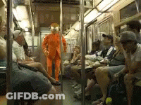 Man In Orange Suit Standing In Train GIF