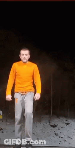 Man In Orange Sweater And Gray Pants On Ledge GIF